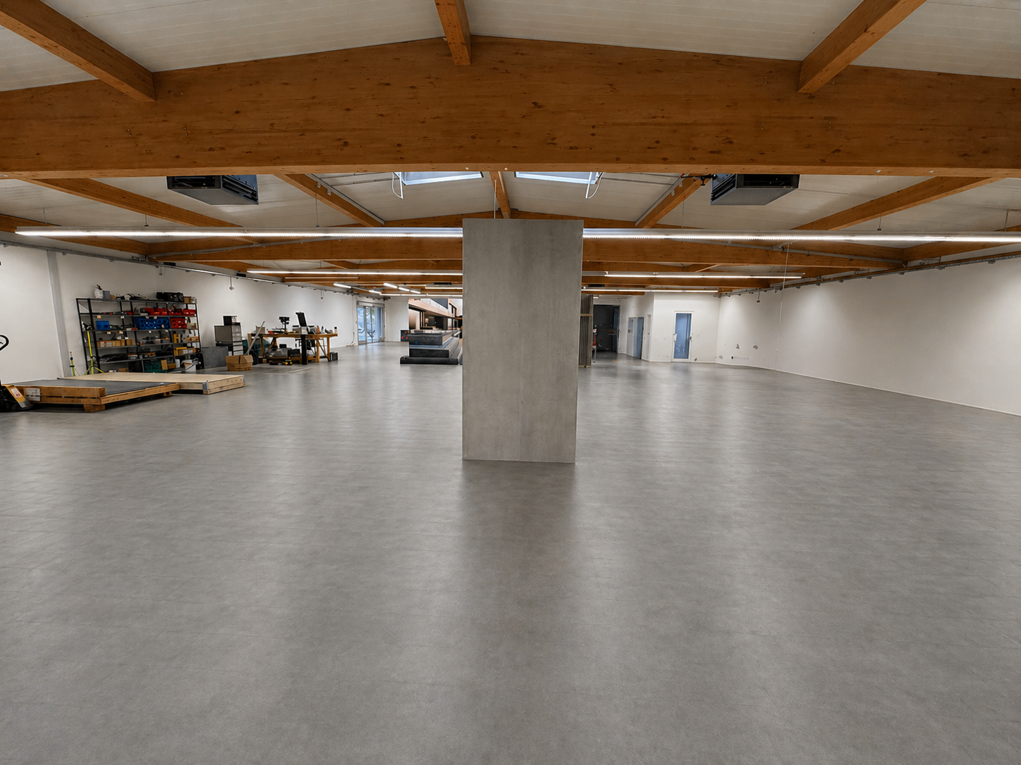 Weitere Hallenansicht mit offener Fläche, Holzträgern und heller Innenraumsituation
